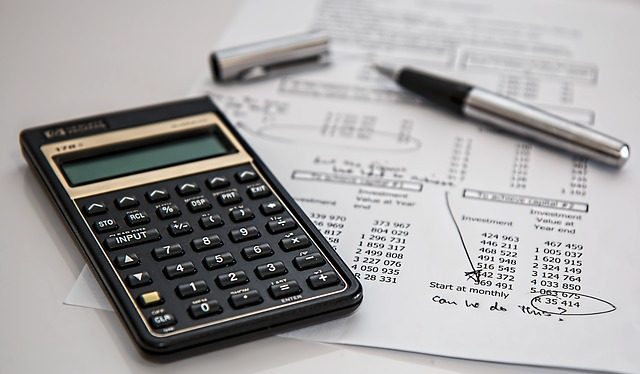 Calculator and pen on desk with paper