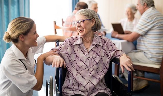 Female nurse smiles while caring for elderly woman in wheelchair