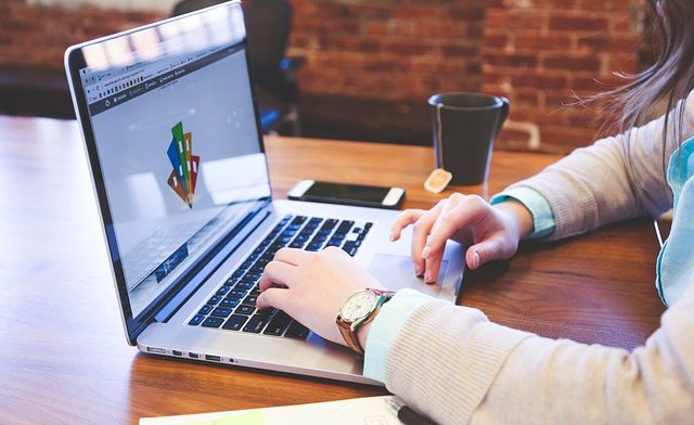 Woman dressed in business attire works on computer at cafe
